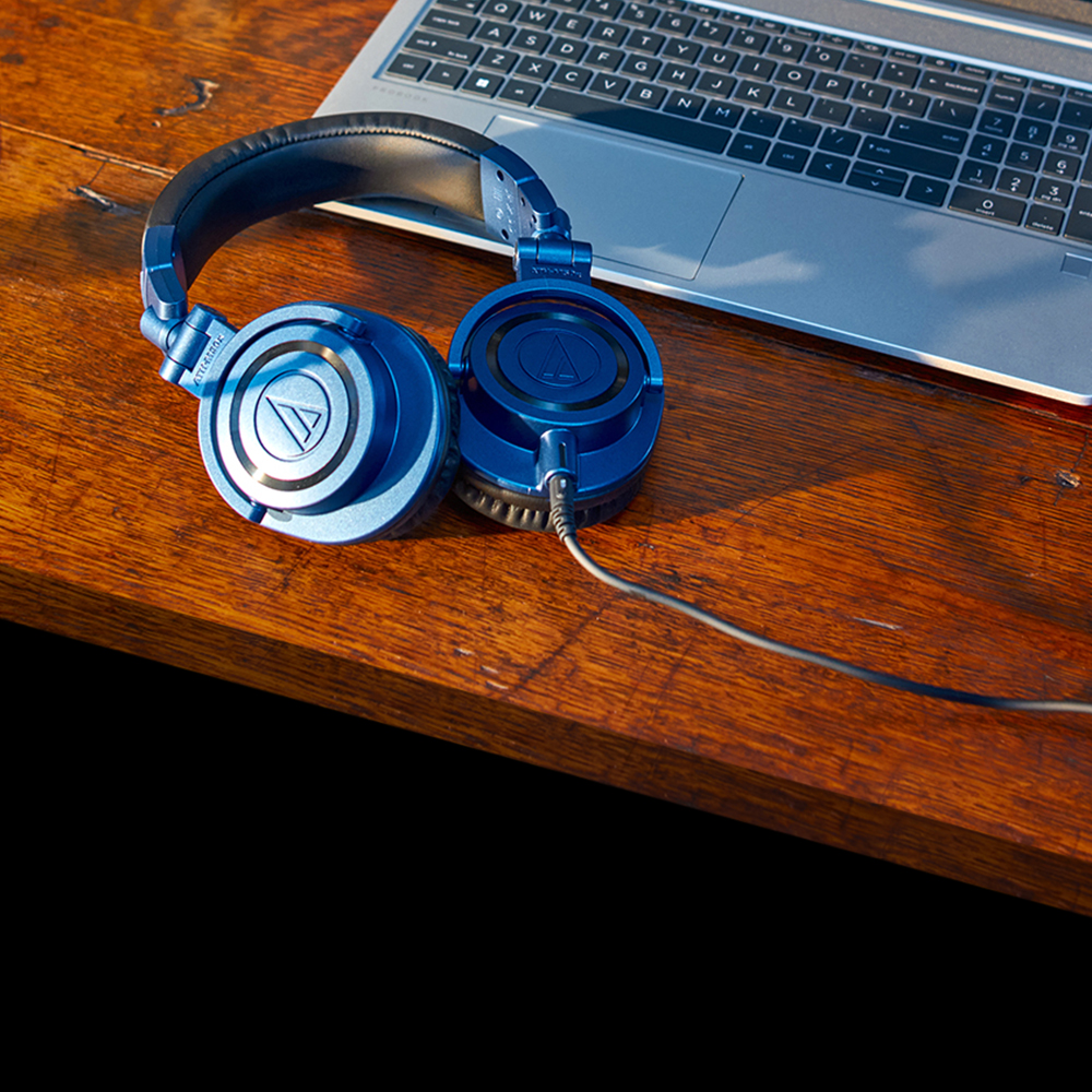 ATH-M50xDS limited edition deep sea blue headphones on table with computer